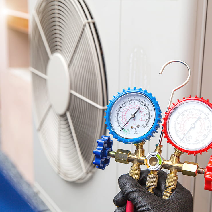 HVAC service gauges connected to an outdoor unit for maintenance, repairs, and system replacement.