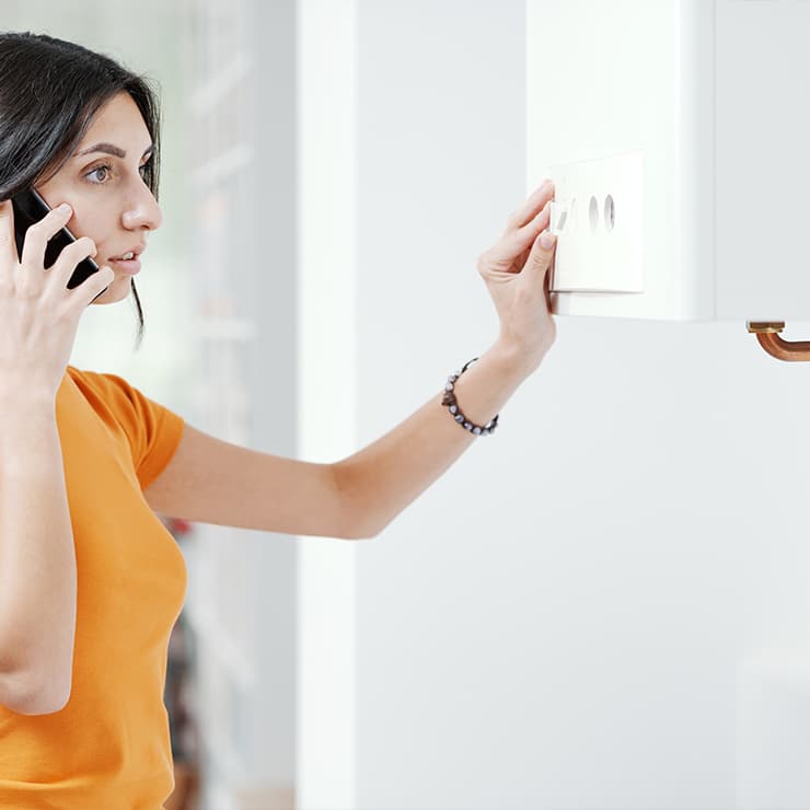 Woman calling for emergency heating repair after checking her home thermostat in Maryland
